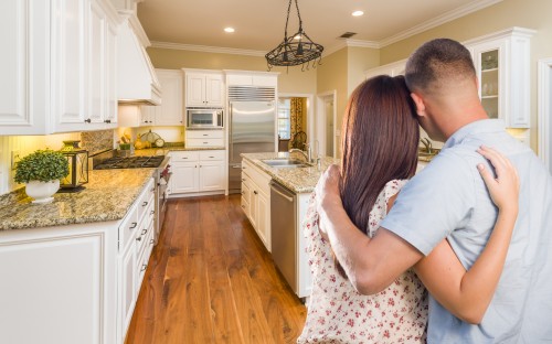 Young Hopeful Military Couple Looking At Beautiful Custom Kitchen.