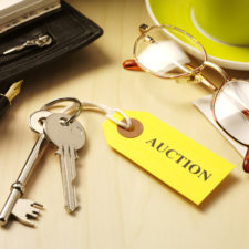 House keys with a auction label, personal items on a wooden table.