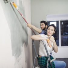 Cheerful young couple have a fun and painting walls at home