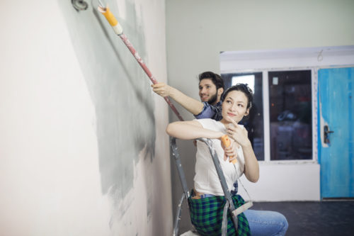 Cheerful young couple have a fun and painting walls at home